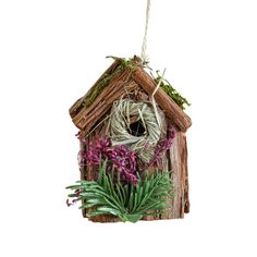 a birdhouse with purple flowers and greenery hanging from it's side on a white background