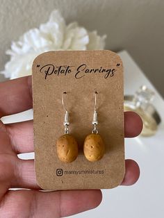 the small wooden earrings are on display in front of a card with a white flower