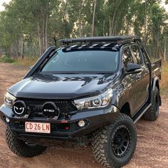 a black truck parked on top of a dirt road