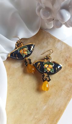 Sicilian style earrings made of: - Sicily Ceramic Coffe Bag (38 mm x 28 mm); - Faceted Crystal (2 mm), black color; - Faceted Citrine Quartz (12 mm x 10 mm), yellow color; - Gold plated 925 Sterling Silver hooks. Lenght : 7 cm / 2,76 inches * SHIPPING * Your order will be shipped within 1-3 business days from your purchase. You can choose between 2 shipping methods: STANDARD SHIPPING (without tracking) and REGISTERED MAIL (with tracking). * GIFT PACKAGING * If you want the gift box, you can buy Luxury Handmade Orange Jewelry, Luxury Amber Drop Earrings, Luxury Yellow Earrings As Gift, Luxury Yellow Earrings For Gift, Elegant Handmade Yellow Earrings, Decoupage Earrings, Sicilian Style, Fashion Designers Famous, Faceted Crystal