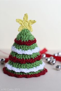 a crocheted christmas tree sitting on top of a table next to silver bells