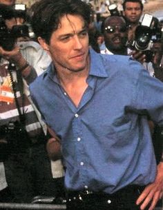 a man in blue shirt and black pants surrounded by photographers