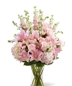 a vase filled with pink flowers sitting on top of a table next to a window