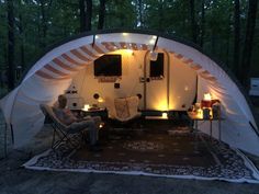 a man sitting in a chair next to a camper trailer with lights on it