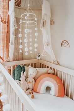 there is a crib with stuffed animals in it and a rainbow decoration on the wall