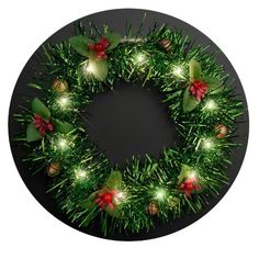 a christmas wreath with lights and holly leaves on a black plate, ready to be used as an ornament