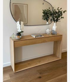 a wooden table with two vases on it and a mirror over the sideboard