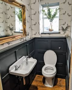 a toilet and sink in a small room with wallpaper on the walls behind it