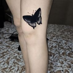 a black and white butterfly tattoo on the right leg, it appears to be an insect