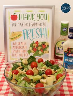 a glass bowl filled with salad sitting on top of a red and white checkered table cloth