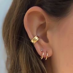 a woman's ear is shown with two small gold hoops on the side