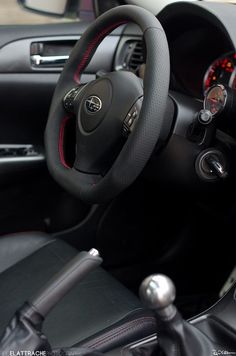 the interior of a car with black leather and red stitching on the steering wheel