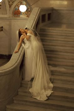 two women dressed in white are kissing on the stairs