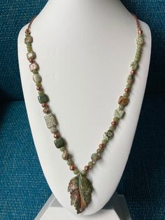 An asymmetrical, natural green Jade necklace, Jasper leaf carved pendant, square green Rhyolite beads and accented with copper beads vintage chain necklace necklace is 30 inches in length and can be made SHORTER! Genuine green Jade 6mm Jasper leaf pendant 1 3/4 X 1 1/4'' Green Rhyolite beads 10 X 10 X 3mm  and ovals 15 X 10 X 3mm and 8 & 10mm faceted rounds All my necklaces are different and would be considered one of a kind. I've been selling on eBay since 2003 Came to Etsy to sell jewelry. Returns and exchange details ► RETURNS / EXCHANGES All items are handcrafted and custom pieces therefore we don't usually accept returns or exchanges on jewelry unless the fault was ours. Screens do not always reflect the same colors as well as seeing them in person. However, I understand that these pi Luxury Jasper Elegant Necklaces, Pearl And Jasper Necklace, Unique Necklaces With Rectangular Natural Stone Pendant, Artisan Necklace With Natural Stones In Rectangular Pendant, Green Jasper Spiritual Jewelry, Bohemian Green Jasper Jewelry, Green Ocean Jasper Bohemian Jewelry, Nature-inspired Jade Pendant Necklace, Green Bohemian Ocean Jasper Jewelry