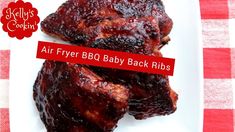 two pieces of bbq baby back ribs on a white plate with red checkered table cloth