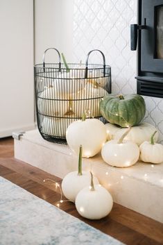 white pumpkins and gourds are sitting on a counter in front of a fireplace