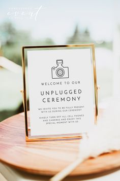 a sign that is on top of a wooden table in front of a window with white feathers