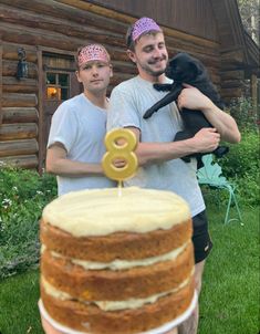 two men standing next to each other holding a cake with a number on the top