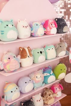 a pile of stuffed animals sitting on top of a bed next to a white headboard