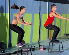 a group of men and women doing exercises in a crossfit gym with ropes