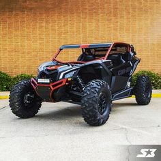 a black and orange can - am off road vehicle parked in front of a building