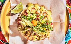 a colorful plate with food on it and a lime wedge next to the plate is half eaten