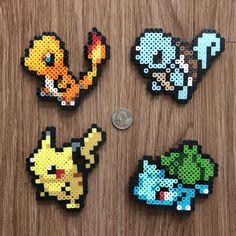 four pixelated pokemon magnets sitting on top of a wooden table next to a penny