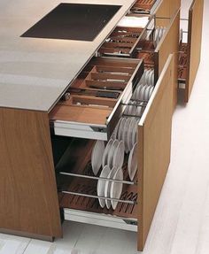 an open drawer in the middle of a kitchen with plates and utensils inside