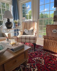 a living room filled with furniture and a large window covered in blue curtains next to a red rug