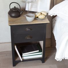 a bedside table with books and a teapot on it