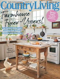 the cover of country living magazine features a kitchen island and white painted cabinets with flowers on it