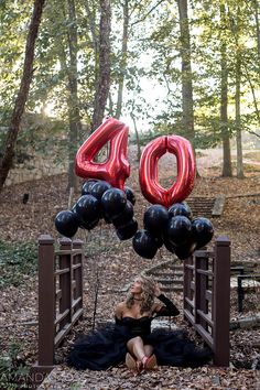 a woman is sitting on the ground with balloons in front of her that say 40