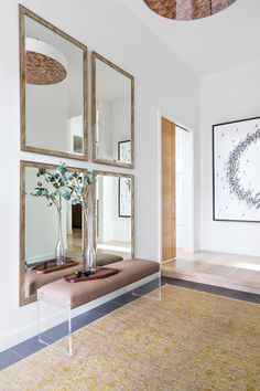 a living room with three mirrors on the wall and a bench in front of it