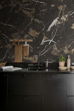 a kitchen with black cabinets and marble walls