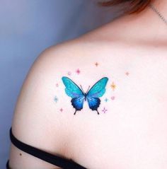 a woman's shoulder with a blue butterfly tattoo on her left shoulder and stars in the background