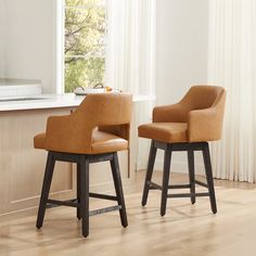 two brown bar stools sitting next to each other in front of a kitchen counter