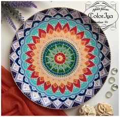 a colorful plate sitting on top of a table next to some beads and flowers in front of it