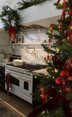 a kitchen decorated for christmas with red and green ornaments on the tree, stove and oven