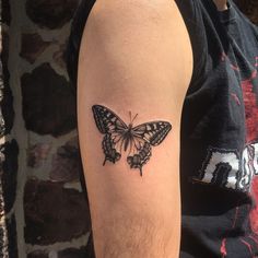 a black and white butterfly tattoo on the left upper half of the right arm,