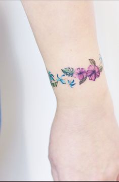 a woman's foot with a flower tattoo on her left ankle and pink flowers on the side