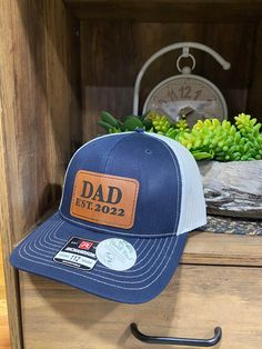 "Personalized Richardson 112 \"DAD\" Leather Patch Hats are a great way to celebrate fatherhood. Get a personalized \"dad\" hat for that father figure in your life, whether it be your father, uncle, brother, nephew, grandfather, etc!  Patches are roughly 3\" x 2\". We apply patches to Richardson 112 SnapBack Trucker Hats. Choose patch color. Choose hat color. LEAVE IN MESSAGE, ------Enter the est date in the personalization section, if more personalization is needed please message or email us at Leather Patch Hat, Patch Hats, Laser Engraved Leather, Patch Hat, Girl Dad, Hat Patches, Father Figure, Dad Caps, Dad Hat