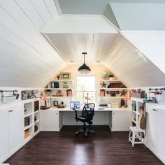 an attic office with white walls and wooden flooring, built in shelving units