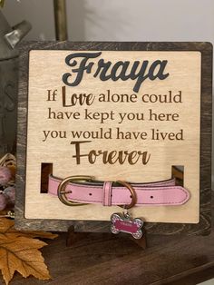 a wooden sign with a dog's name on it and a pink leather collar