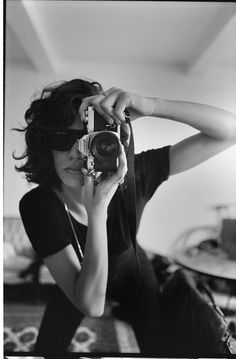 black and white photograph of a woman holding up a camera