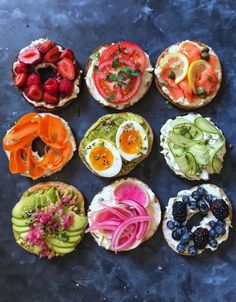 an assortment of sandwiches with fruit and vegetables on them sitting on a blue table top