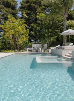 an empty swimming pool with lounge chairs and umbrellas in the shade on a sunny day