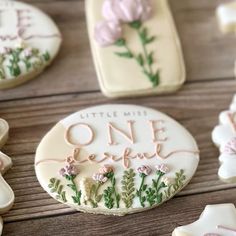 cookies decorated with flowers and the words little miss, one bite written in white frosting