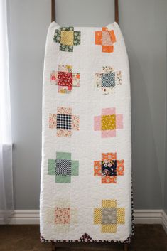 a white quilt is hanging on a clothes rack