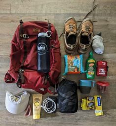 the contents of a backpack laid out on top of a wooden floor next to shoes