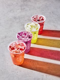 four different colored cups are lined up on the floor